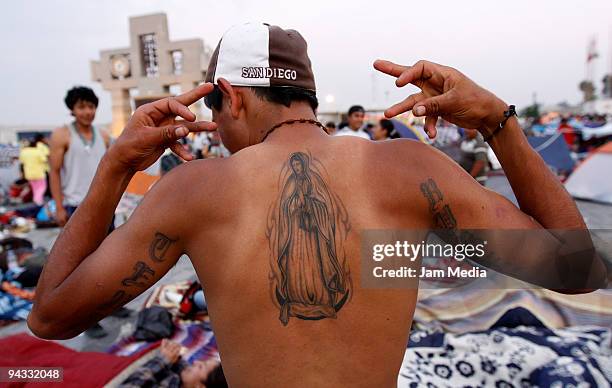 Man shows his tattoo in front of the Basilica of Guadalupe during the celebration of the Virgin of Guadalupe on December 12, 2009 in Mexico City,...