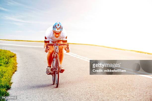 männliche radfahrer fährt professionelle rennen fahrrad bergab - mikkelwilliam stock-fotos und bilder