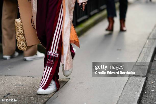 Guest wears Adidas red striped sportswer pants, white sneakers shoes, during London Fashion Week February 2018 on February 16, 2018 in London,...