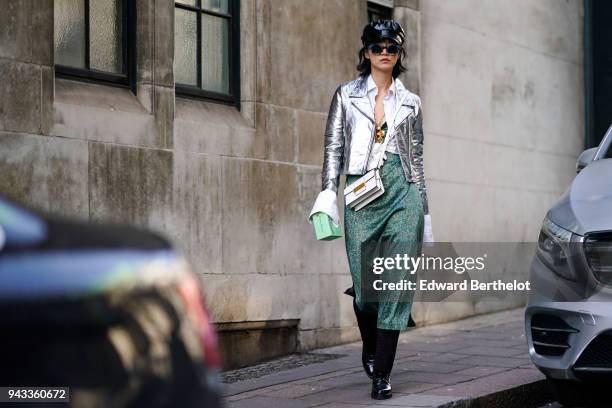 Guest wears a black cap hat, sunglasses, a silver shiny glitter blazer jacket, a green skirt, a white bag, during London Fashion Week February 2018...