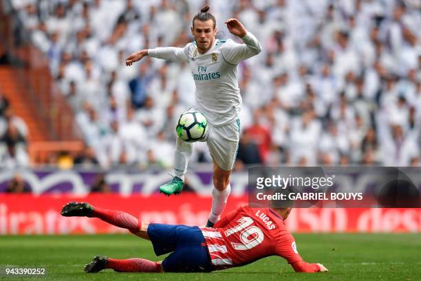 Real Madrid's Welsh forward Gareth Bale jumps over Atletico Madrid's French defender Lucas Hernandez during the Spanish league football match between...
