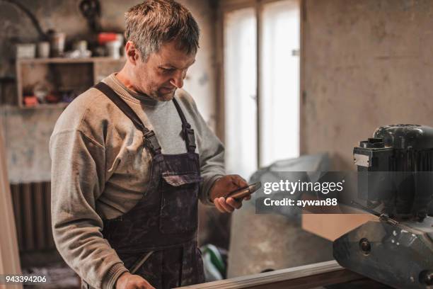 mature carpenter using phone - repairman phone stock pictures, royalty-free photos & images