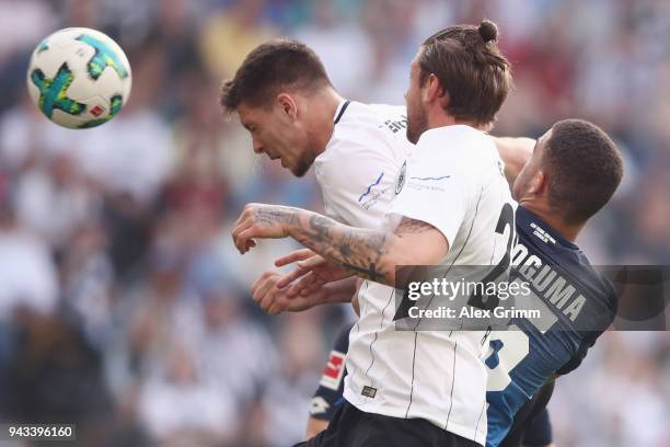 Kevin Akpoguma of Hoffenheim jumps for a header with Luka Jovic and Marco Russ of Frankfurt during the Bundesliga match between Eintracht Frankfurt...