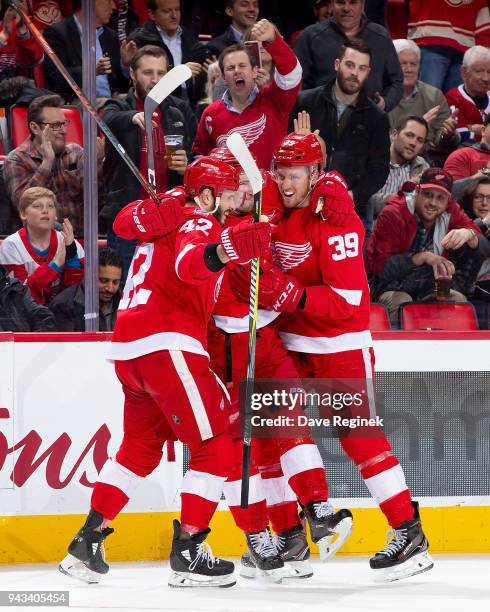 Dylan Larkin of the Detroit Red Wings celebrates a first period goal with teammates Andreas Athanasiou and Anthony Mantha during an NHL game against...