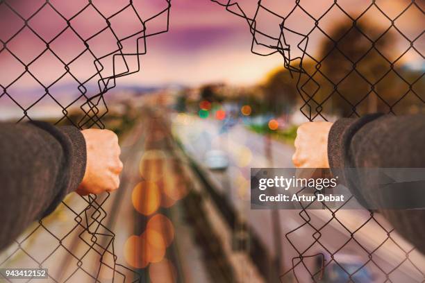 urban picture taking from personal perspective of guy opening grid fence. - barricade stockfoto's en -beelden