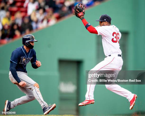 Eduardo Nunez of the Boston Red Sox leaps for an overthrown ball as Brad Miller of the Tampa Bay Rays evades the tag during the fourth inning of a...