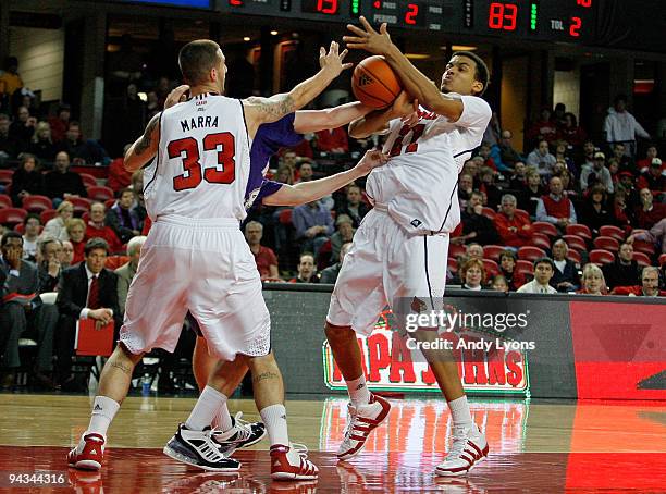 Mike Marra and Jared Swopshire of the Louisville Cardinals and Jake Robinson of the Western Carolina Catamounts reach for a loose ball during the...