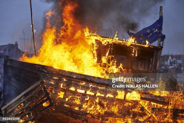 The remains of a small boat flying European flags is burnt on a bonfire during a demonstration in Whitstable, southeast England on April 8, 2018...