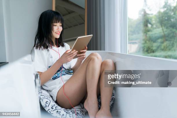 chinese woman listening to music in bathtub - eskapismus stock-fotos und bilder