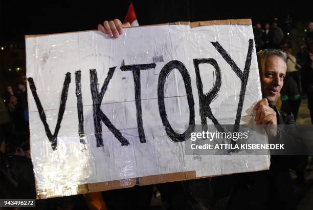 Supporter of the governing FIDESZ party lifts his home-made placard reading 'Viktory' as Hungarian Prime Minister Viktor Orban celebrates from the...