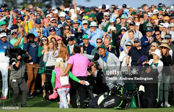 Patrons cheer as Patrick Reed of the United States and his wife Justine walk off the 18th green after his 15-under-par 71 during the final round to...