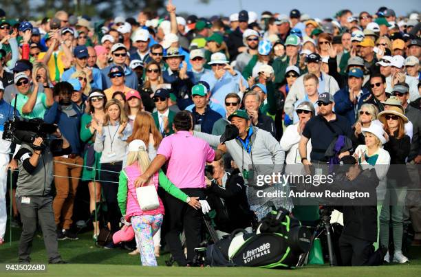 Patrons cheer as Patrick Reed of the United States and his wife Justine walk off the 18th green after his 15-under-par 71 during the final round to...