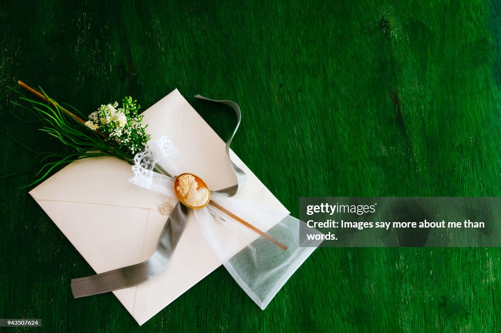 Wedding invitation with a small miosótis bouquet with cameo over green background.