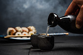 Man pouring sake into sipping bowl