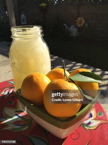 bowl of fresh lemons and a mason of jar of lemonade on a sunny day - frasco para conservas fotografías e imágenes de stock