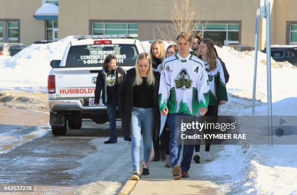 People, including a young man wearing a Humboldt Broncos jersey, approach the Uniplex April 8, 2018 in Humboldt, Canada, prior to a memorial vigil...