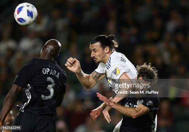Zlatan Ibrahimovic of Los Angeles Galaxy heads the ball over the defense of Ike Opara and Graham Zusi of Sporting Kansas City during the second half...