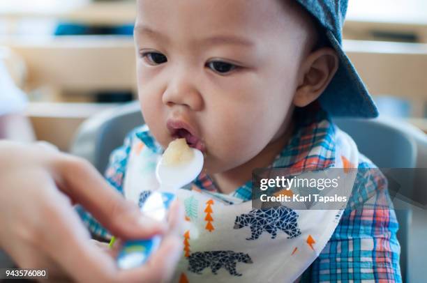 a mother is feeding her baby with solid food - filipino family eating stock pictures, royalty-free photos & images