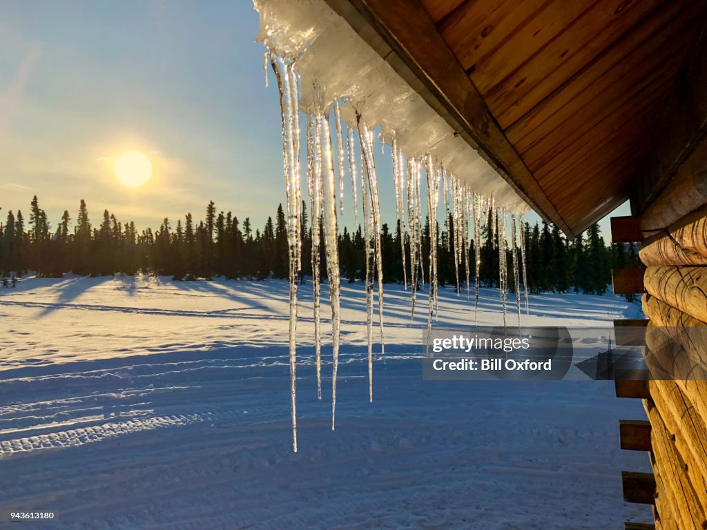 Eiszapfen an Dach und Sonnenuntergang