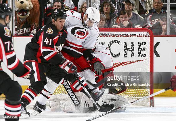 Manny Legace of the Carolina Hurricanes makes a pad save as Jonathan Cheechoo of the Ottawa Senators screens on the shot and Tim Gleason of the...