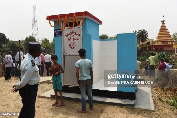 This photo taken on April 8 shows a private security guard and villagers gathering around a newly built public toilet by Boeing India, under its...