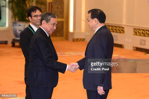 Yohei Kono, head of the Japanese Association for the Promotion of International Trade shakes hands with Chinese Premier Li Keqiang before their...