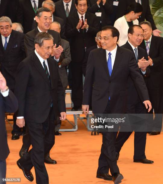 Yohei Kono, head of the Japanese Association for the Promotion of International Trade walks with Chinese Premier Li Keqiang before their meeting on...