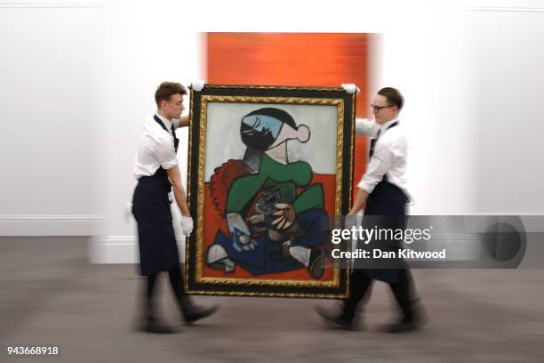 Sotheby's employees carry a painting by Pablo Picasso entitled 'Femme au Chien' during a UK preview of the 'Impressionist and Modern Art' sale on...