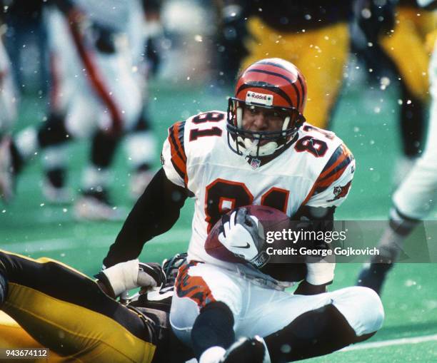 Wide receiver Carl Pickens of the Cincinnati Bengals holds on to the football as he is tackled after catching a pass as snow falls during a game...