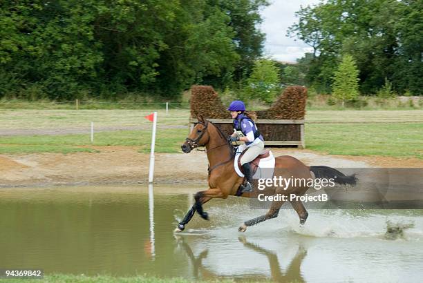 junge frauen in cross country water jump - vielseitigkeitsprüfung geländestrecke stock-fotos und bilder