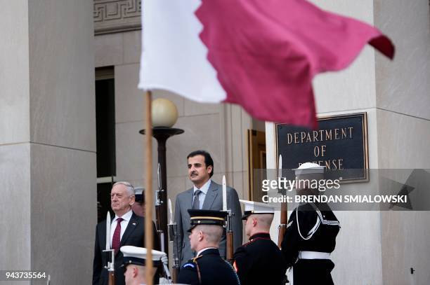 Secretary of Defense James Mattis and Qatar's Emir Sheikh Tamim Bin Hamad Al-Thani listen to Qatar's national anthem during an honor cordon at the...