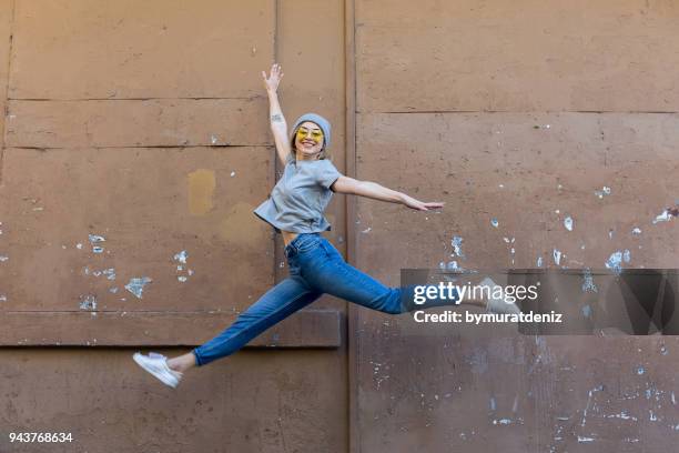 joven saltando delante de pared - saltar fotografías e imágenes de stock