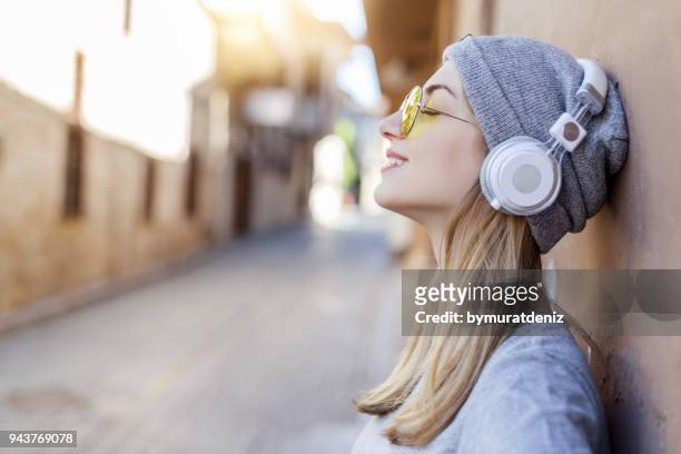 壁の近くに若い女性の聞く音楽 - straight hair ストックフォトと画像