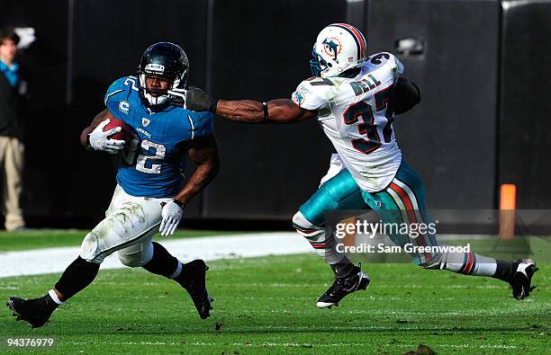 Maurice Jones-Drew of the Jacksonville Jaguars runs the ball against Yeremiah Bell of the Miami Dolphins during the game at Jacksonville Municipal...