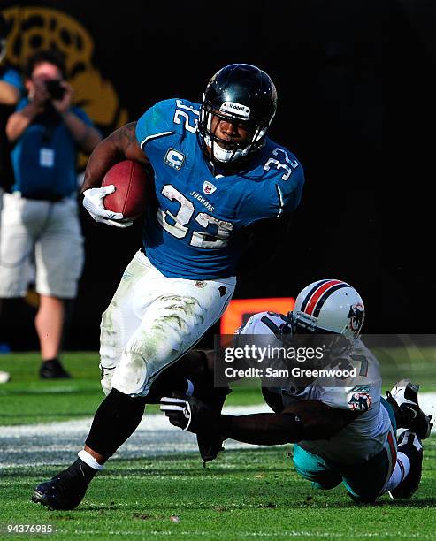 Maurice Jones-Drew of the Jacksonville Jaguars runs the ball against Yeremiah Bell of the Miami Dolphins during the game at Jacksonville Municipal...