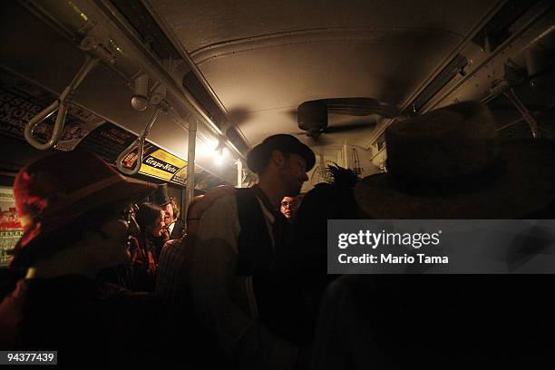 Lone incandescent bulb is all that illuminates costumed revelers riding after other bulbs briefly went out on an antique subway train during a...