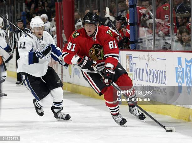 Marian Hossa of the Chicago Blackhawks takes the puck up the boards as Jeff Halpern of the Tampa Bay Lightning follows behind on December 13, 2009 at...