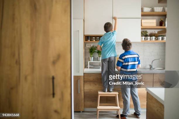 brothers stealing cookies in kitchen - child cookie jar stock pictures, royalty-free photos & images