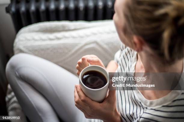 young woman enjoying coffee and relaxing on a sofa - drink coffee stock pictures, royalty-free photos & images