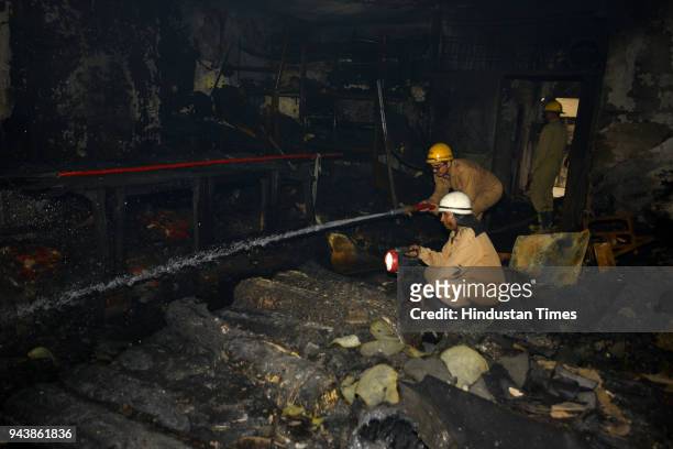 Delhi Fire Service personnel investigate after a fire broke out at a Raja Park shoe factory in Sultan Puri on April 9, 2018 in New Delhi, India. Four...
