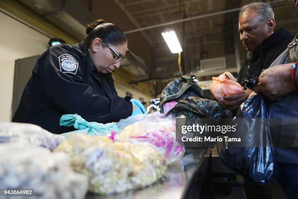 Customs and Border Protection officer inspects items of a couple entering the United States on foot at the San Ysidro port of entry on April 9, 2018...