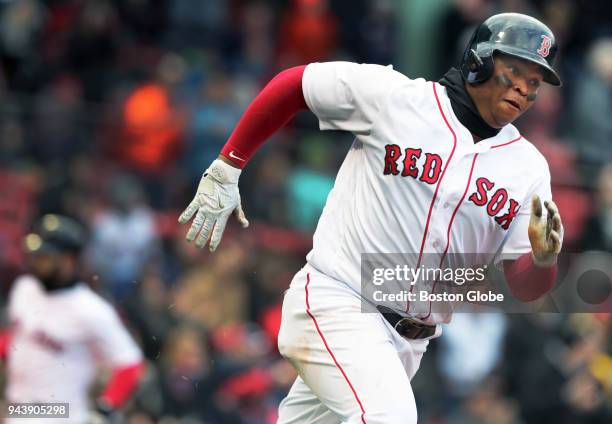 Boston Red Sox player Rafael Devers runs between bases on a two RBI double, as teammate Mitch Moreland heads to the plate in the background at far...