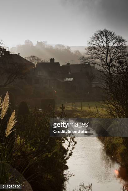 a small brook runs behind houses beneath ruins of peveril castle, castleton - silentfoto sheffield stock pictures, royalty-free photos & images