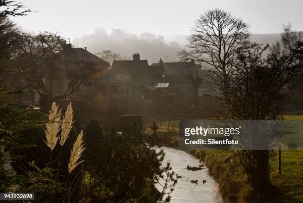 a small brook runs behind houses beneath ruins of peveril castle, castleton - silentfoto sheffield stock pictures, royalty-free photos & images