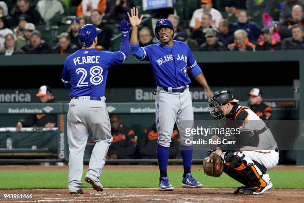 Catcher Caleb Joseph of the Baltimore Orioles looks on as Steve Pearce of the Toronto Blue Jays celebrates with Curtis Granderson after hitting a two...
