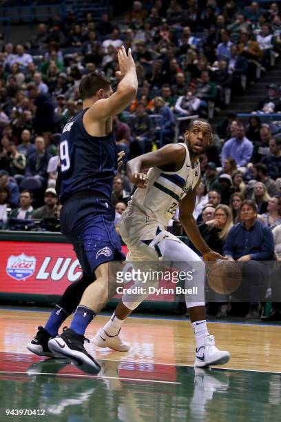 Khris Middleton of the Milwaukee Bucks dribbles the ball while being guarded by Nikola Vucevic of the Orlando Magic in the first quarter at the...