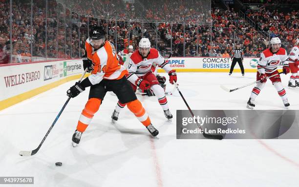 Sean Couturier of the Philadelphia Flyers skates the puck along the goal line against Trevor van Riemsdyk of the Carolina Hurricanes on April 5, 2018...