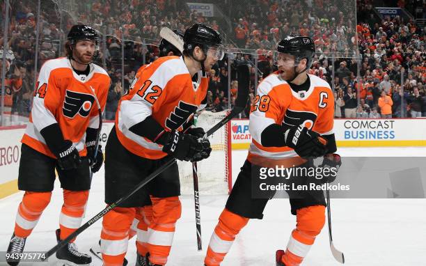 Claude Giroux of the Philadelphia Flyers reacts with teammates Michael Raffl and Sean Couturier following a second period goal against the Carolina...