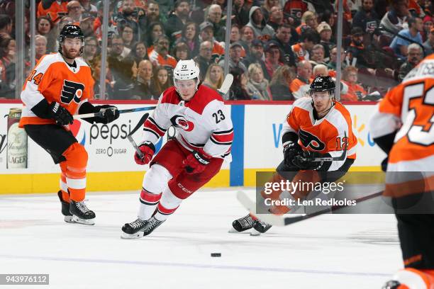 Sean Couturier and Michael Raffl of the Philadelphia Flyers skate after the loose puck against Brock McGinn of the Carolina Hurricanes on April 5,...