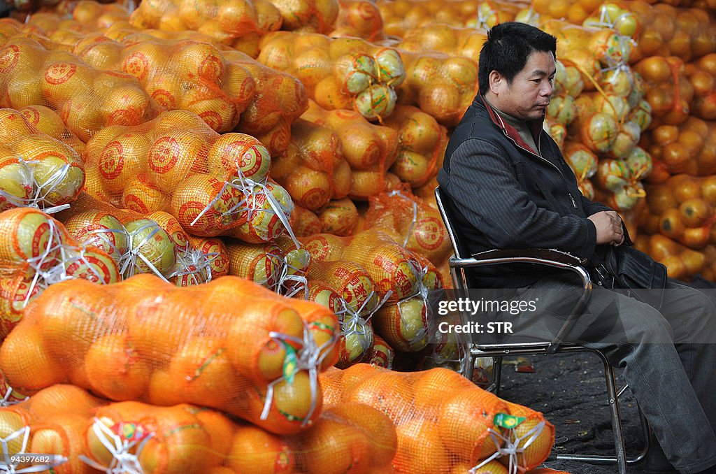 A Chinese fruit seller sits with his sto